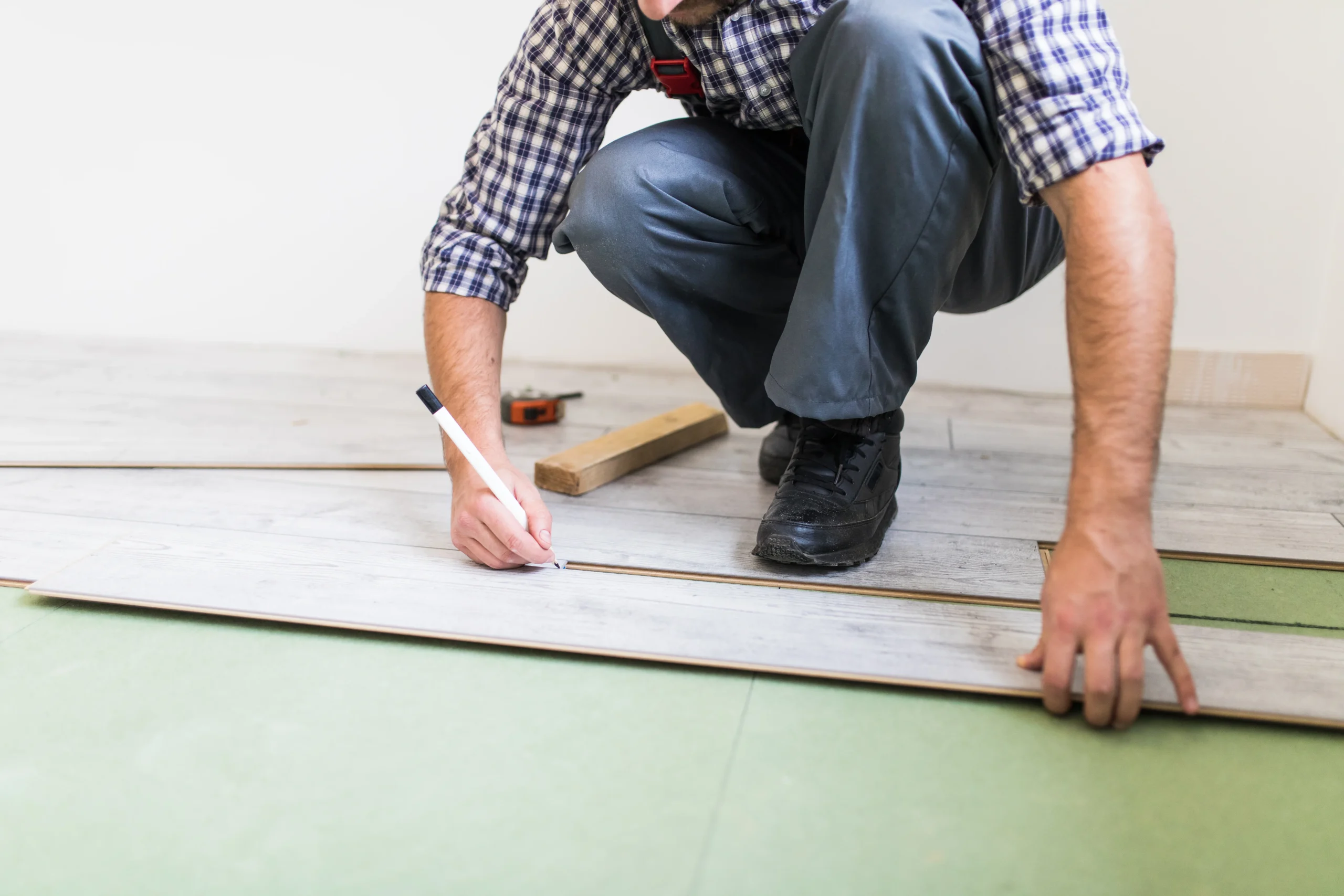 joven-trabajador-revestimiento-suelo-con-pavimento-laminado